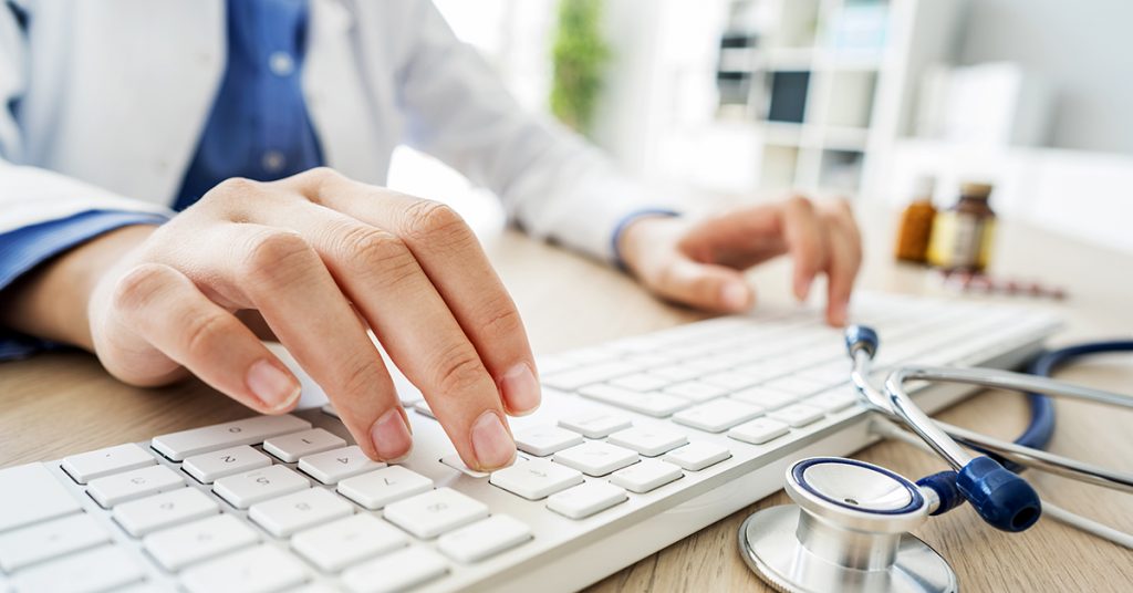 Female doctor typing on computer; blog: IT Must-Haves for Every Doctor’s Office
