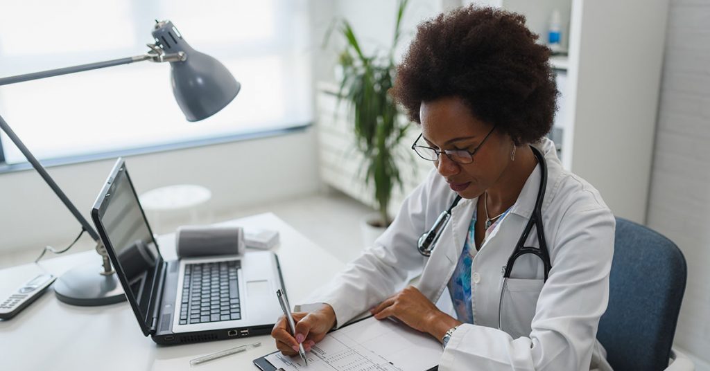 Serious concentrated African American doctor working in her office; blog: 6 Ways to Improve Medical Office Efficiency in the New Year