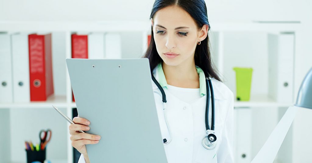 Close up view of female doctor holding clipping pad and reading patient history. Healthcare and medical concept; blog: How to Select the Right Clinical Documentation Partner